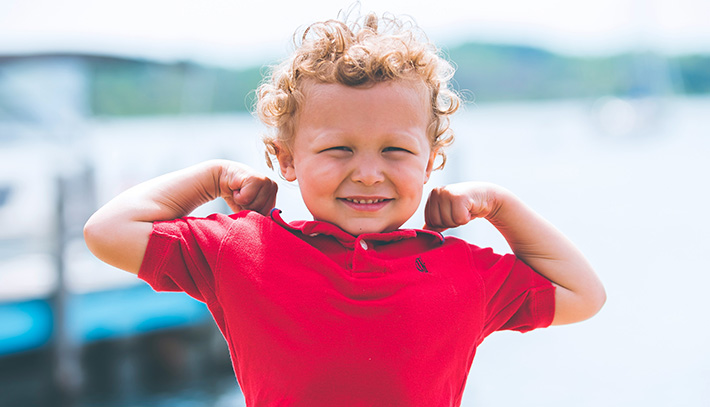 Small boy flexing his muscles, showing resilience